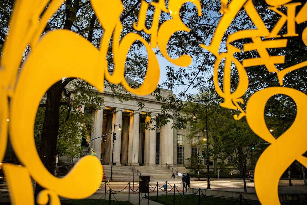 Yellow numeric symbols in the Alchemist sculpture frame the columns at 77 Massachusetts Avenue.