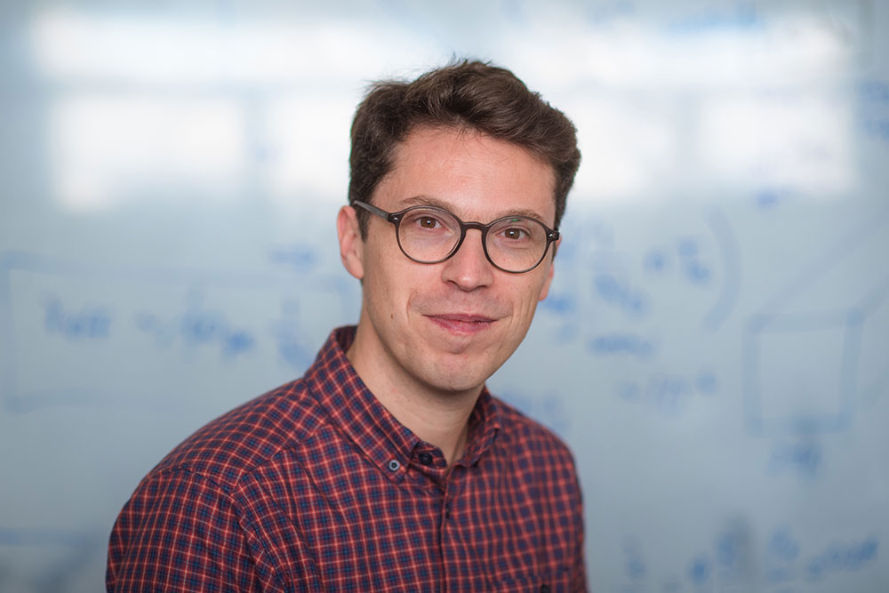 Portrait of faculty member Nuno Loureiro in front of a whiteboard with writing on it