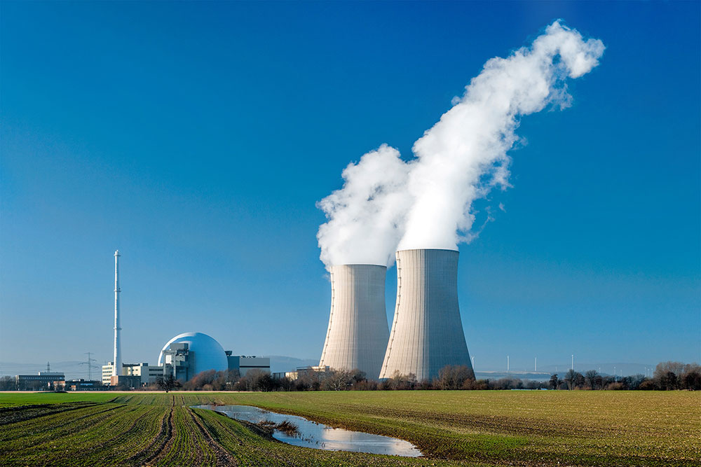 nuclear power plant in a field with wind turbines in the distance