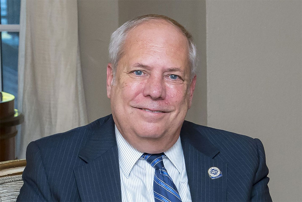 Portrait of John Kelly in a blue suite and tie in an office