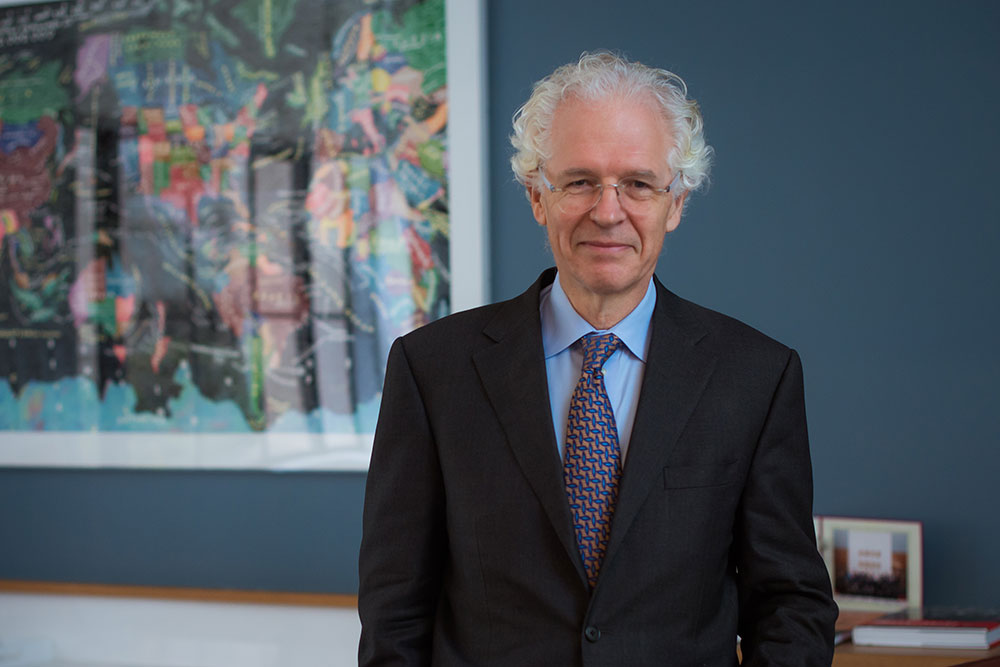 Richard K Lester standing in an office with a framed print of an illustrated world map in the background to the left, MIT