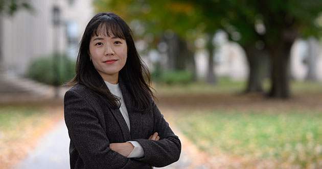 Graduate  student Youyeon Choi, arms folded outside on a path with trees on the right, MIT